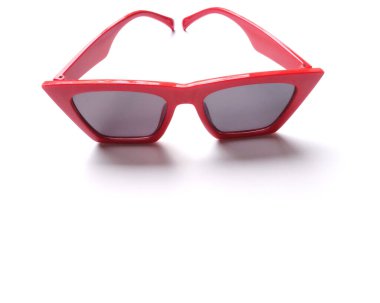 Üst ve düz beyaz arka planda kırmızı çerçeveli güneş gözlüğü. Aksesuarlar, modern kadın modası.