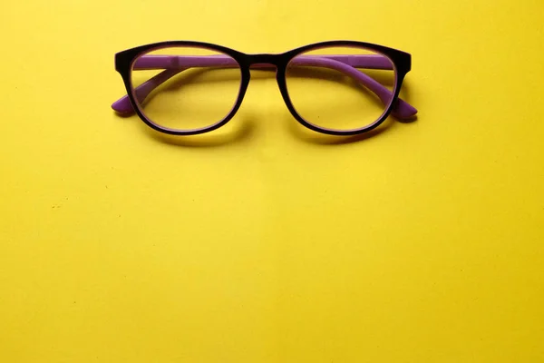 top view a purple framed eyeglasses isolate on a yellow background