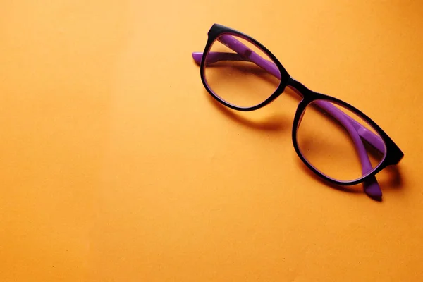 copy space a purple framed eyeglasses isolate on a orange background