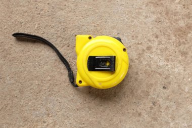 flat lay and top view one a yellow tape measure on cement background