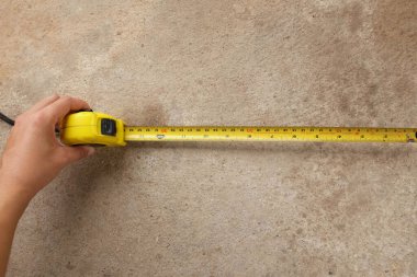 Measuring tool. Hand with a tape measure isolated on cement background