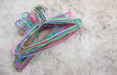 Boşluğu kopyala çimento arka planda renkli plastik elbise askıları
