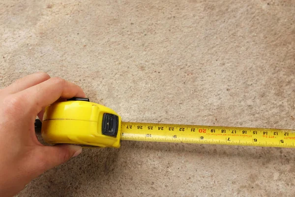 Measuring tool. Hand with a tape measure isolated on cement background