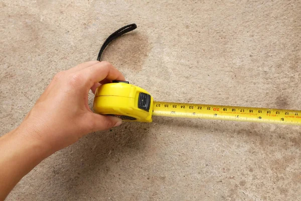 Measuring tool. Hand with a tape measure isolated on cement background