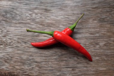 Üst ve düz organik kırmızı biber yatağı (kırmızı biber, uzun kırmızı biber, mahmuz biberi) kesme tahtasının üzerinde koyu arkaplan ile izole edilmiş.