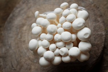 top view and flat lay of fresh organic white beech mushrooms or shimeji mushrooms isolate on a wooden chopping board