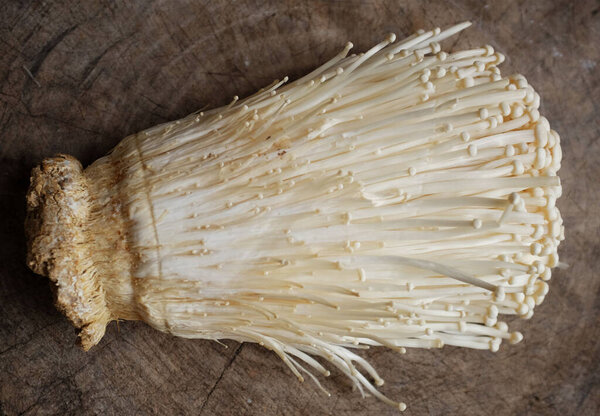 top view and close up of fresh organic white fresh golden needle mushroom or enoki mushroom isolated on on a wooden chopping board