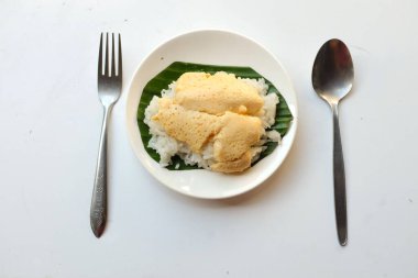top view a sticky rice with steamed custard in banana leaves in a white plate isolate on a white background.Thai desserts