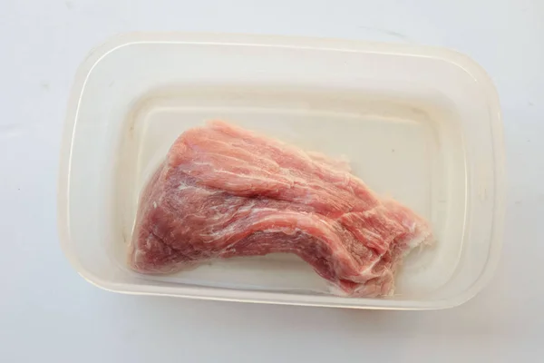 Pork meat in a plastic box on a white background.