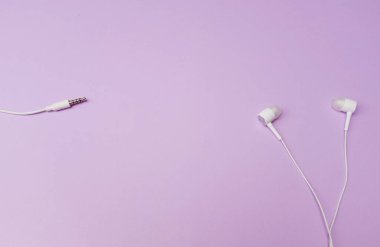 white music headphones ,earphones with headset on isolated bright purple pastel background. Music concept. Top view