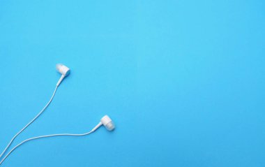 white music headphones ,earphones with headset on isolated bright blue background. Music concept. copy space