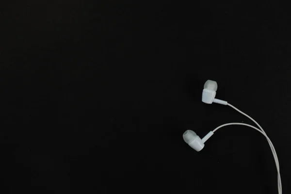 white music headphones ,earphones with headset on isolated bright black background. Music concept. Top view