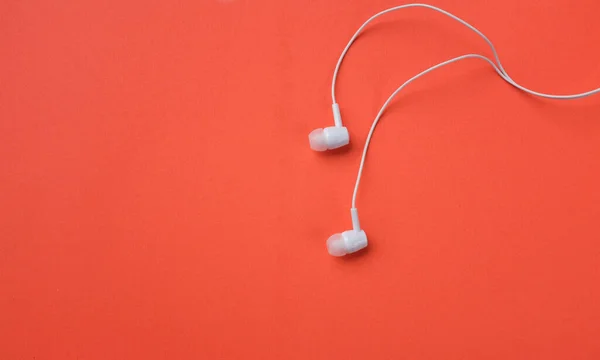 white music headphones ,earphones with headset on isolated bright orange background. Music concept. Top view