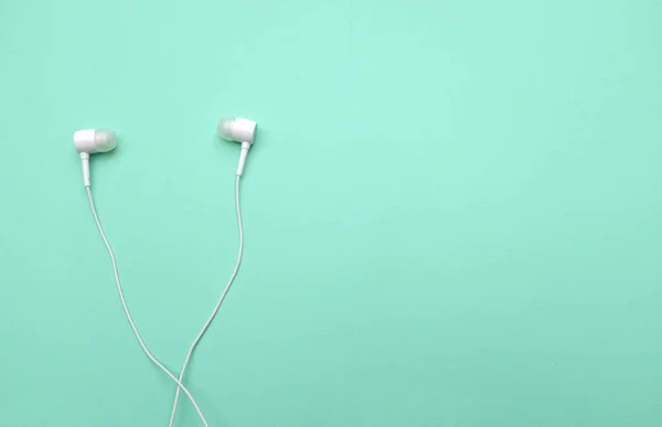 white music headphones ,earphones with headset on isolated bright green pastel background. Music concept. copy space