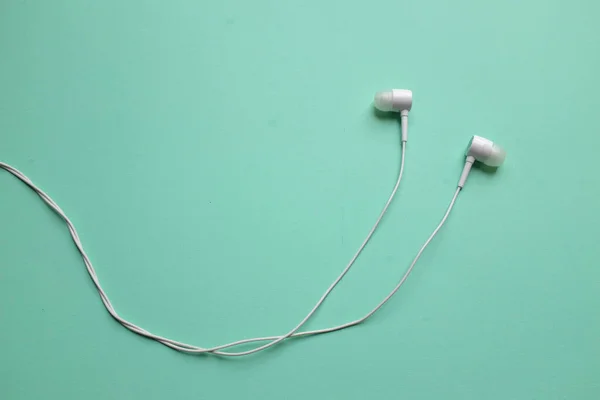 white music headphones ,earphones with headset on isolated bright green pastel background. Music concept. Top view