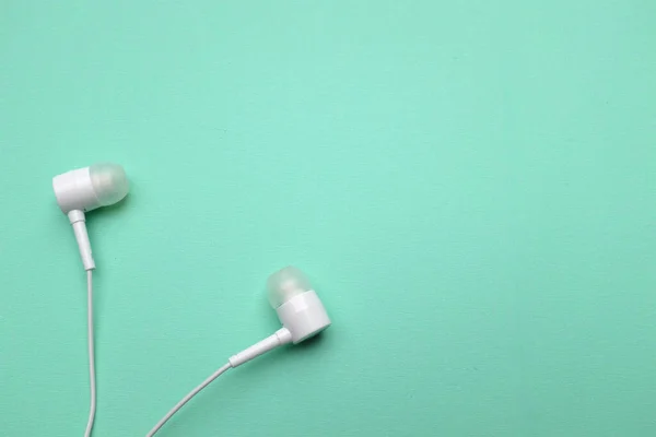 white music headphones ,earphones with headset on isolated bright green pastel background. Music concept. copy space