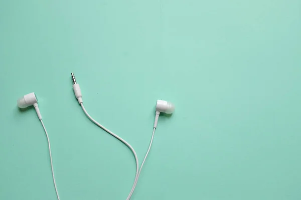 white music headphones ,earphones with headset on isolated bright green pastel background. Music concept. Top view