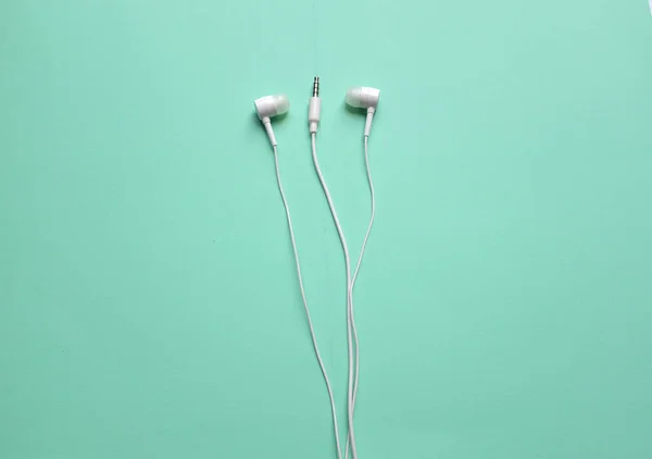 white music headphones ,earphones with headset on isolated bright green pastel background. Music concept. Top view