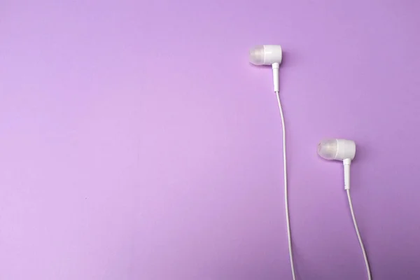 white music headphones ,earphones with headset on isolated bright purple pastel background. Music concept. Top view