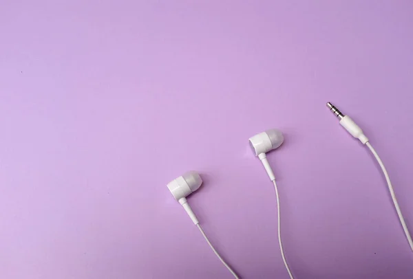 white music headphones ,earphones with headset on isolated bright purple pastel background. Music concept. flat lay
