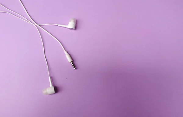 white music headphones ,earphones with headset on isolated bright purple pastel background. Music concept. Top view