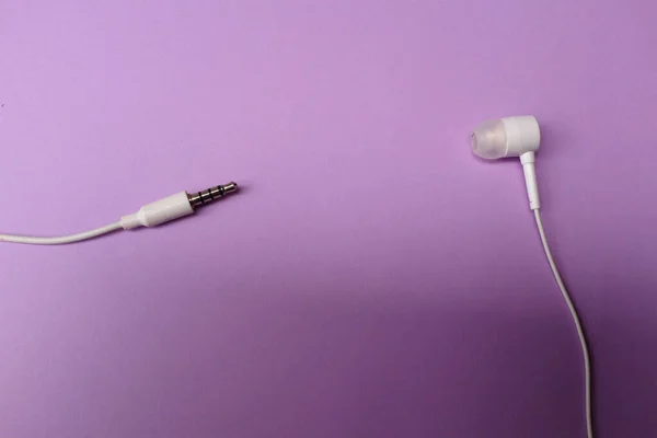 white music headphones ,earphones with headset on isolated bright purple pastel background. Music concept. Top view