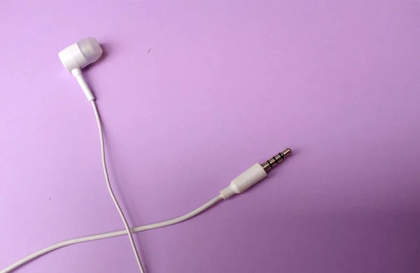 white music headphones ,earphones with headset on isolated bright purple pastel background. Music concept. Top view