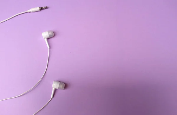 white music headphones ,earphones with headset on isolated bright purple pastel background. Music concept. flat lay