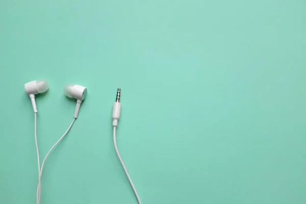 white music headphones ,earphones with headset on isolated bright green pastel background. Music concept.