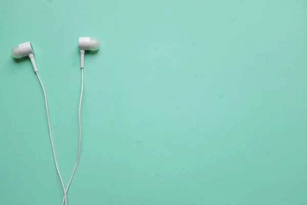 white music headphones ,earphones with headset on isolated bright green pastel background. Music concept.
