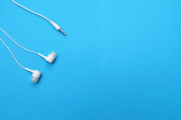 white music headphones ,earphones with headset on isolated bright blue background. Music concept. Top view