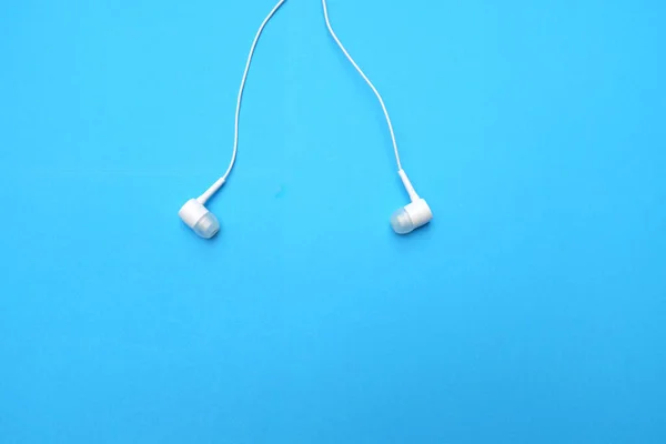 white music headphones ,earphones with headset on isolated bright blue background. Music concept. Top view