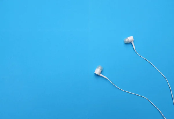 white music headphones ,earphones with headset on isolated bright blue background. Music concept. copy space