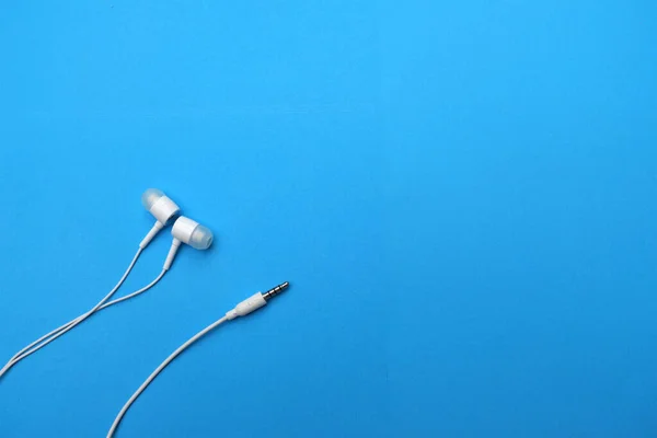 white music headphones ,earphones with headset on isolated bright blue background. Music concept. copy space