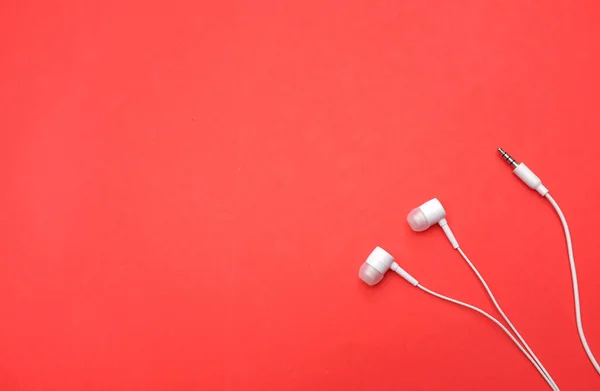 white music headphones ,earphones with headset on isolated bright red background. Music concept. Top view
