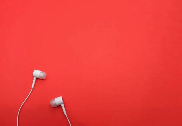 white music headphones ,earphones with headset on isolated bright red background. Music concept. Top view