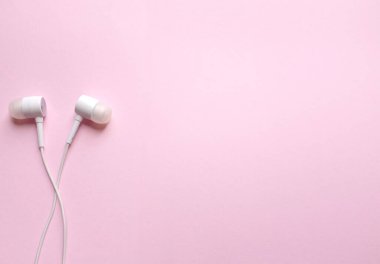 Yukarıdaki beyaz kulaklıklardan, kulaklıklardan, kulaklıklardan izole edilmiş pembe pastel arka planda.