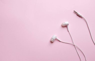 Yukarıdaki beyaz kulaklıklardan, kulaklıklardan, kulaklıklardan izole edilmiş pembe pastel arka planda.