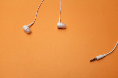 Yukarıdaki beyaz kulaklıklardan, kulaklıklardan, kulaklıklardan izole edilmiş turuncu arka plandan.
