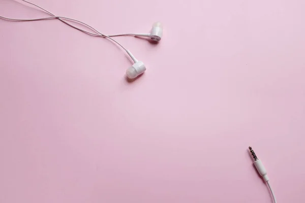 独立したピンクのパステルの背景にヘッドセットを持つトップビューの白いヘッドフォン イヤフォン イヤホン — ストック写真