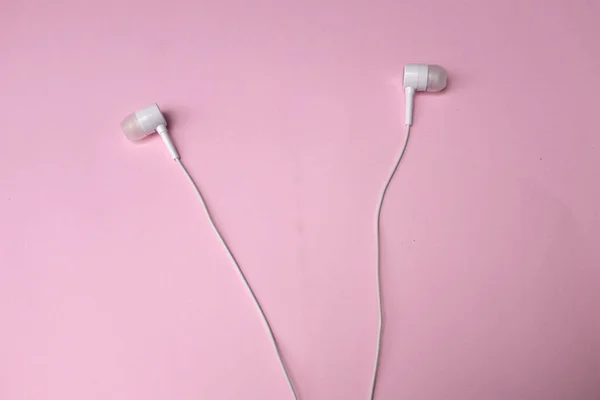 上の白いヘッドフォン イヤフォン イヤホン ヘッドセットで隔離されたピンクのパステルの背景 — ストック写真