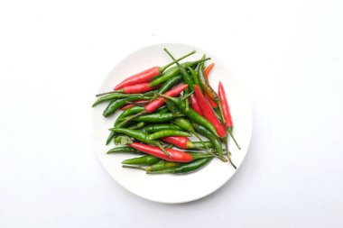 Beyaz bir arkaplanda izole edilmiş seramik tabakta taze kırmızı ve yeşil acılı biber.