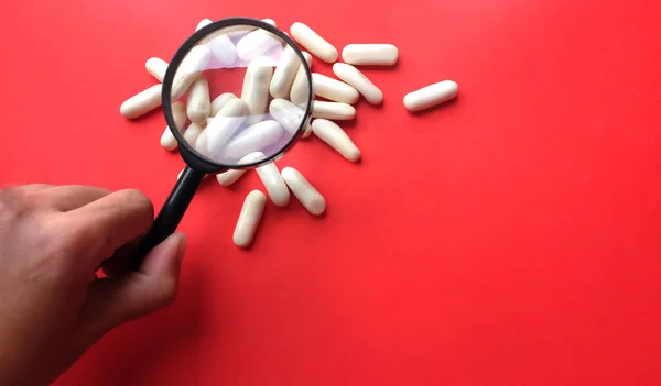 Tabletten Tabletten Kapseln Unter Der Lupe Isolieren Auf Rotem Hintergrund — Stockfoto
