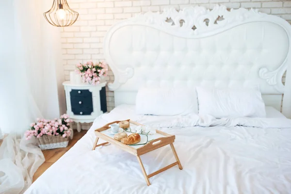 Provence bedroom in white colors with tasty breakfast in bed. French croissant