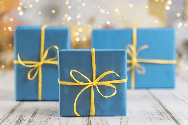 Festive background with three gift boxes wrapped in blue paper and tied with yellow ribbon — Stock Photo, Image