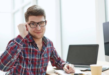 Gözlüklü genç adam, sabah erkenden defterini hazırlıyor, işleri yoluna koyuyor.