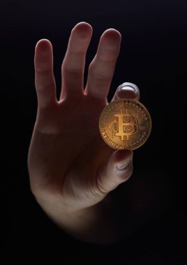 A hand holds a coin isolated on a black background