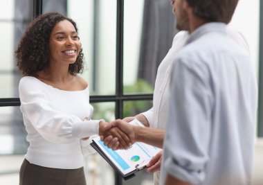 Smiling multiethnic businesspeople shaking hand in office.