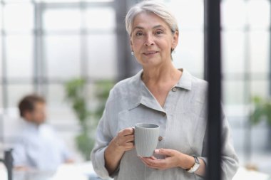 close-up mature woman holding a cup in the office.