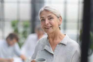 close-up mature woman holding a cup in the office.
